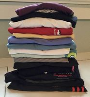 Stacked assorted women's activewear folded including tops of various colors