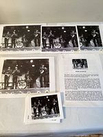 Five black and white photos of The Beatles on stage arranged on a table with a typed story sheet describing the origin of the photographs and autographs.