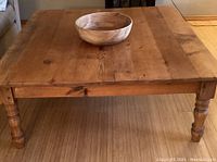 Full view of rustic knotty pine square low table with large wooden bowl on top.