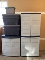 Overall view of two beige cabinets stacked side by side with Rubbermaid bins on left and small tote atop