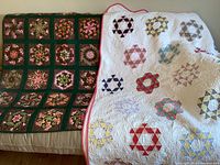 Two quilts draped on sofa: left dark green floral block quilt and right white ring patchwork quilt