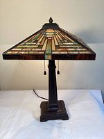 Front view of lamp showing square pyramid stained glass shade and bronze metal base