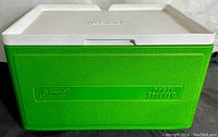 Front view of green and white Coleman Party Stacker Cooler showing logos and textured surface