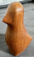 Side view showing the smooth carved modernist shape and wood grain texture of the teak bird sculpture.