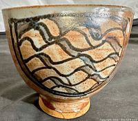 Front side view of ceramic vase showing brown abstract wavy pattern on speckled beige glaze surface.