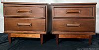 Front view of both nightstands side by side showing matching design, drawers, handles, and tapered legs.