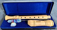 Soprano recorder disassembled in blue-lined black case with cleaning brush and cork grease.
