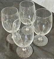Four clear deep wine glasses shown grouped together from a slight side angle to show shape and transparency.