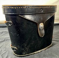 Closed vintage black leather carrying case with visible stitching and snap closure on top flap