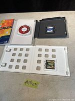 Open plastic case holding PSP UMD game 'Lumines' disc and open Nintendo DS game case with cartridge inside on a table surface with black background.