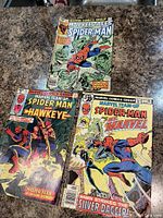 Three vintage Spider-Man comic books laid out on surface, showing cover art and prices.