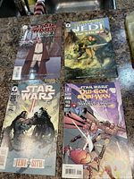 Photo showing the lot of 4 Star Wars comic books on a countertop: Star Wars Episode I: The Phantom Menace, Tales of the Jedi: The Sith War, Jedi vs Sith, and Qui-Gon & Obi-Wan: Aurorient Express.