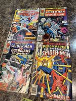 Four vintage Spider-Man comic books laid out on a surface showing front covers and normal wear.