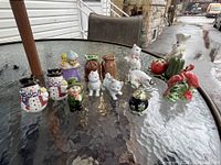 All salt and pepper shakers arranged on a glass table outdoors, showing a variety of whimsical and animal-shaped designs.