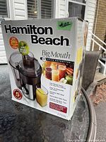 Box showing Hamilton Beach branding, Big Mouth series, juice extractor model number 67008C, and main features including large feed chute and 5 year warranty option.