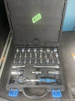 Opened socket set case showing organized sockets of different sizes, ratchet handle, extension bars, and adapter.