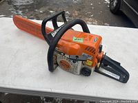 Side view of Stihl MS 170 chainsaw with orange plastic bar cover on table