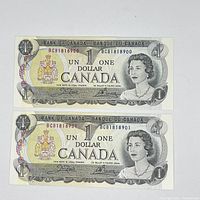 Front side of two Canadian $1 dollar bills with consecutive serial numbers BCB1818900 and BCB1818901 showing Queen Elizabeth II portrait and coat of arms.
