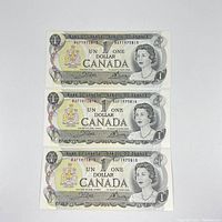 Front side of three uncirculated consecutive Canadian $1 bills showing Queen Elizabeth II portrait and serial numbers BAF1975813, BAF1975814, BAF1975815.