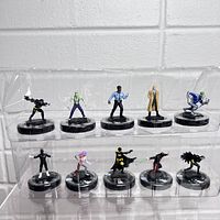 Full set of 11 Heroclix superhero miniatures in two rows inside clear plastic packaging, posed on black bases with stats.