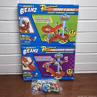 Photo showing 2 Mighty Beanz racetrack sets in original boxes (Super S-Bend and Collision Chaos) and a sealed bag with 18 Mighty Beanz toy beans