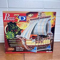 Front of the sealed box showing the puzzle 3D pirate ship that glows in the dark by Wrebbit with 358 pieces.