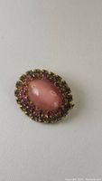 Top view of antique oval cat's eye pin with outer row of pink and colorless stones.