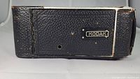 Side view of the Kodak No. 1 Series 2 camera showing black leatherette body with Kodak badge and some surface wear.