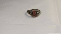 Antique sterling silver ring with a red enameled PHSS shield emblem and Victorian details shown at slight angle.