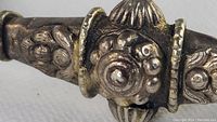 Close-up of the decorative repousse pendant flower and soldering detail on the bracelet