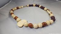Full view of handmade KYL necklace laid out flat showing round beads in multiple colors and central kidney-shaped bead.