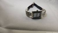 Photo of a rectangular vintage Sunrise wristwatch with a silver-tone decorated case and 23mm pin bracelet.