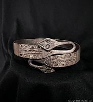 View of the vintage metal bracelet featuring double snakehead design and stamped patterns on a black background.