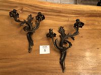 Pair of vintage Italian brass wall candle sconces shown on wooden surface from overhead angle.