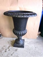 Front view of the heavy cast iron planter showing its urn shape and decorative rim.