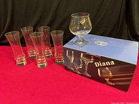 Set of one brandy glass and five flute glasses displayed with brandy glass on box and five flutes beside it.