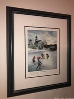 Framed hockey scene print hanging on wall showing full view with dark wood frame and beige matting.
