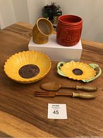 Full view of all kitchenware items on wooden table showing salt pig, Ball Mason jar, sunflower bowl, candy dish, and wood salad servers