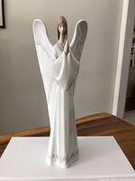 Front view of the Nao by Lladro angel figurine showing the angel with outstretched wings and hands in prayer.