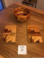 Photo of the two rectangular marquetry wall art panels with landscape motif and the signed turned wood bowl on a wooden table.