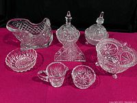 Full set of 10 pinwheel crystal cut leaded glassware pieces with variety of dishes and containers displayed on magenta cloth.
