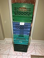 Stacked four plastic milk crates showing colors and wear.