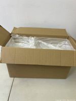 Brown cardboard box filled with stacked clear organizer trays wrapped in plastic.