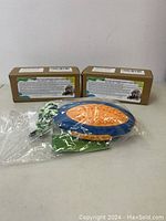 One rugby-shaped pink and blue dog chew toy sealed in plastic, with an attached knotted rope in green, white, and blue colors, displayed in front of two product boxes.