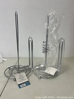 Two GreenCo chrome paper towel holders, one still in plastic wrapping, displayed on white background.