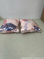 Two soft flamingo blankets folded and sealed in plastic packaging, showing they are new and unused.
