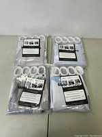 Four sealed shower curtain sets packaged in plastic, visible white hooks.