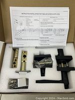 Opened box showing black matte tubular lever door lock components laid in foam cutouts with installation instructions on top.