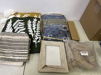 Full lot overview showing multiple home decor items including throws, cushions, frame, and box.