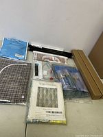 Full view of all items in the lot including fabric, mounting hardware, gift wrapping boxes, shower curtain package, and precision knives.